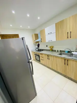 a kitchen with a stainless steel refrigerator and wooden cabinets at appart à côté de la gare du train in Marrakech