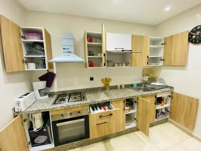 a kitchen with wooden cabinets and a counter top at appart à côté de la gare du train in Marrakech