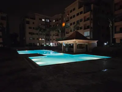 an empty swimming pool at night with buildings at Luxueux appartement Marrakech au cœur de l hivernage in Marrakech