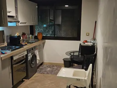 a kitchen with a washing machine and a table and chairs at Luxueux appartement Marrakech au cœur de l hivernage in Marrakech