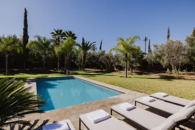 a swimming pool with two lounge chairs next to a yard at Villa de luxe Sahara in Marrakech