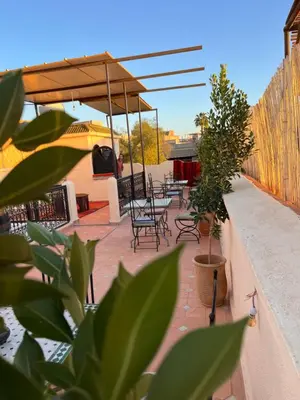 a patio with tables and chairs and an umbrella at Riad Black Doors in Marrakech