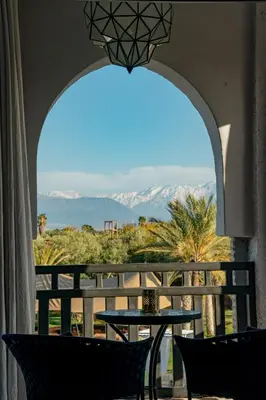 an arched window with a table and a view of the mountains at Palais Anthea Boutique Hotel & Spa in Marrakech