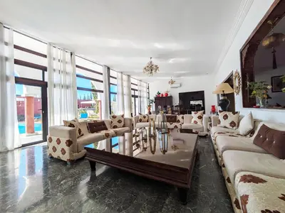 a living room with couches and a table and windows at Villas Green in Marrakech