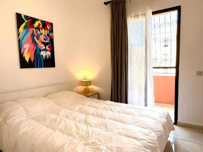 a bedroom with a white bed and a window at Appartement Dalila in Marrakech