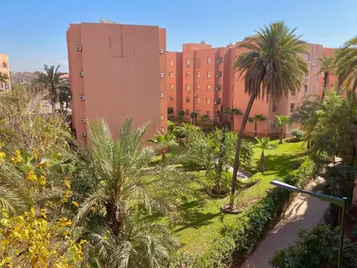 a park with palm trees and a large building at Appartement Dalila in Marrakech