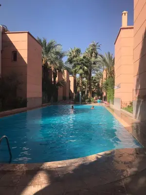 a large swimming pool with palm trees in the background at Appartement dans résidence avec piscine in Marrakech