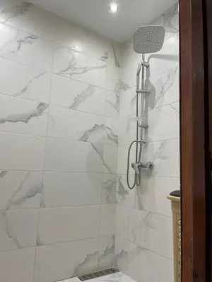 a bathroom with a shower with white marble walls at Appartement dans résidence avec piscine in Marrakech