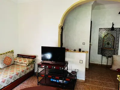 a living room with a couch and a tv at Appartement dans résidence avec piscine in Marrakech