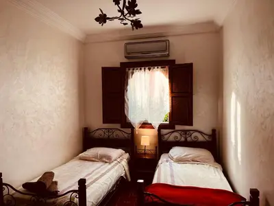 two beds in a small room with a window at Appartement dans résidence avec piscine in Marrakech