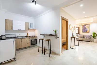 a kitchen and living room with a counter and stools at Magnificent Apartment in Gueliz - 100% Equipped in Marrakech