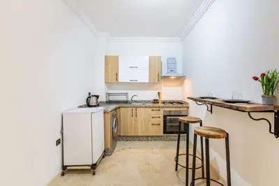 a kitchen with a white refrigerator and two bar stools at Magnificent Apartment in Gueliz - 100% Equipped in Marrakech