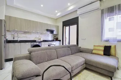 a living room with a couch and a kitchen at Les Jardins Sakar - Marrakech - Deux Chambres Exceptionnelle in Marrakech