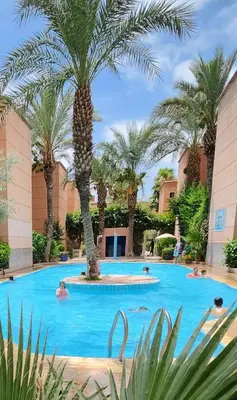 a pool with palm trees and people swimming at Riad with Outdoor Swimming Pools in Marrakech