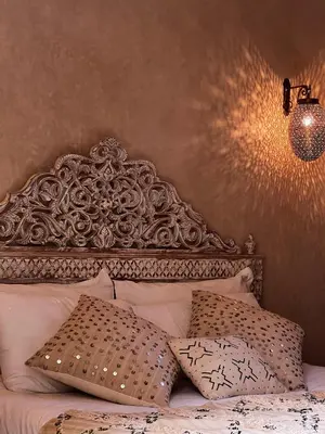 a bed with an ornate headboard and two pillows at Riad with Outdoor Swimming Pools in Marrakech
