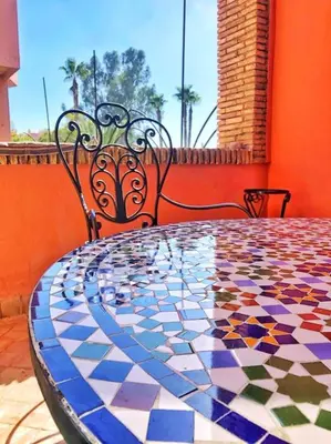a mosaic table with two chairs and a glass table top at Magnifique Duplex En Plein Hivernage à Marrakech in Marrakech