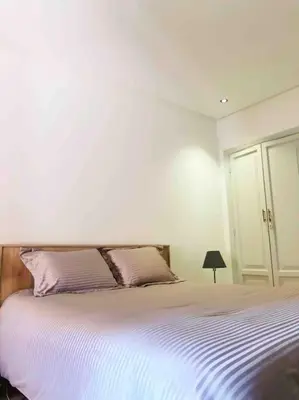 a white bedroom with a large bed with purple pillows at Magnifique Duplex En Plein Hivernage à Marrakech in Marrakech