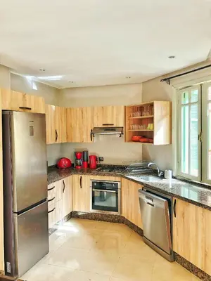 a kitchen with wooden cabinets and stainless steel appliances at Magnifique Duplex En Plein Hivernage à Marrakech in Marrakech
