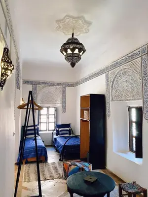 a bedroom with two beds and a chandelier at Riad Sidi Radoine in Marrakech