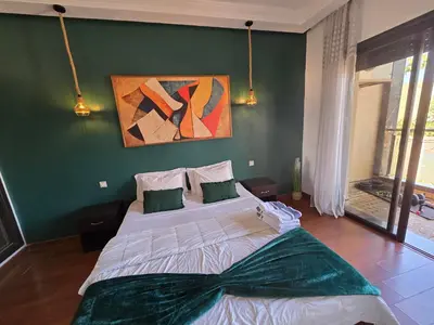 a bedroom with a large bed with a green wall at Bagatelle House 2 in Marrakech