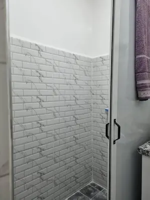 a bathroom with a shower with a white brick wall at proche aéroport, idéal pour travailler in Marrakech