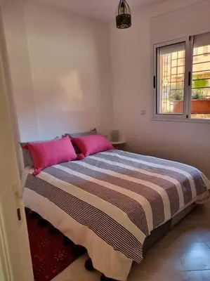 a bedroom with a bed with pink pillows and a window at proche aéroport, idéal pour travailler in Marrakech