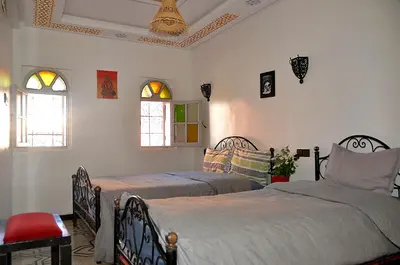 a bedroom with two beds and two windows at Araf House in Marrakech