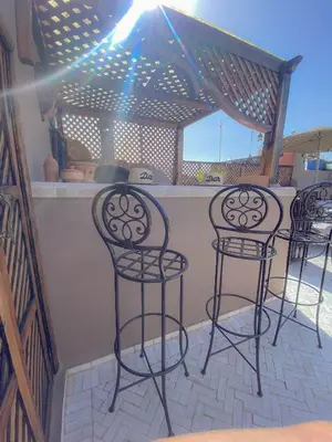 three black bar stools on a patio with a counter at Riad Dar Marrakcha in Marrakech