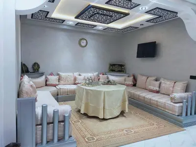 a living room with a table and couches and a tv at Appartement de luxe à 7 min de Centre de ville a petit prix pour passer un agréable séjour in Marrakech