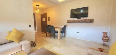 a living room with a table and a tv on the wall at Appartement tout neuf en plein centre de Marrakech in Marrakech