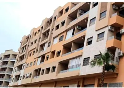 a large apartment building with a palm tree in front of it at Appartement tout neuf en plein centre de Marrakech in Marrakech