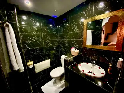 a black tiled bathroom with a toilet and a sink at Riad Dar IMANE in Marrakech