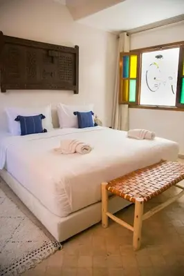 a bedroom with a large white bed and a bench at Riad Sabria in Marrakech