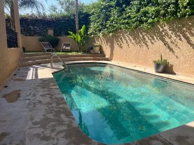 a swimming pool with blue water in a backyard at Marrakech le joyau villa piscine privée jardin in Marrakech