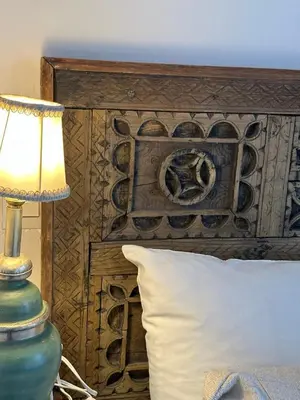 a bed with a wooden headboard with a lamp and a pillow at Riad Dar Malwan Hotel and Massage in Marrakech
