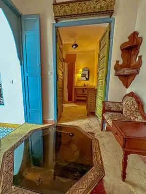 a living room with a couch and a table and a mirror at Riad Dar Malwan Hotel and Massage in Marrakech