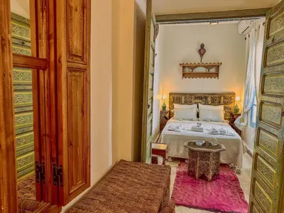 a bedroom with a bed and a table in a room at Riad Dar Malwan Hotel and Massage in Marrakech