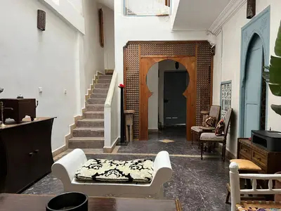 a living room with a table and chairs and stairs at Riad Dar Malwan Hotel and Massage in Marrakech