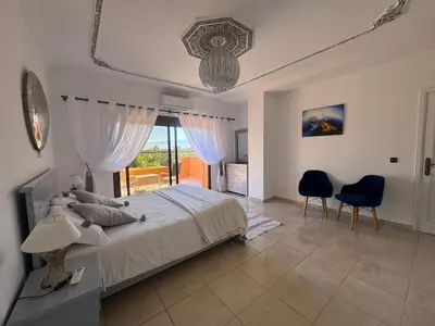 a bedroom with a large bed and two chairs at Maison Jannate Louise in Marrakech