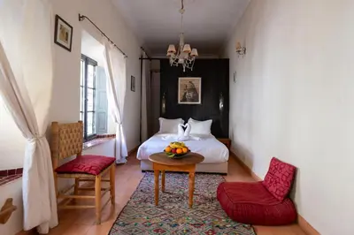 a bedroom with a bed and a table and chairs at Riad le Jardin de Mina in Marrakech
