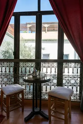 a balcony with a table and two chairs and a window at Riad le Jardin de Mina in Marrakech