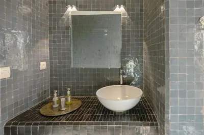 a blue tiled bathroom with a sink and a mirror at Riad le Jardin de Mina in Marrakech