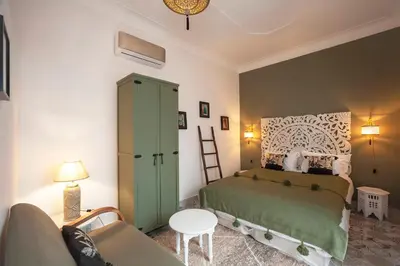 a bedroom with a green bed and a couch at Magnifique Riad Julilu Privatise au coeur de la Medina 11P in Marrakech
