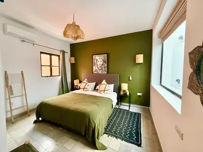 a bedroom with a bed with a green wall at Maison Meurisse JUJ in Marrakech