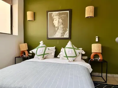 a bedroom with a large bed with green walls at Maison Meurisse JUJ in Marrakech
