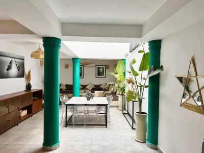 a living room with green columns and a table at Maison Meurisse JUJ in Marrakech