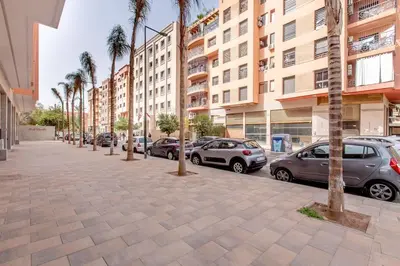 a street with parked cars and palm trees and buildings at New! Marvellous'n modern flat in Marrakech