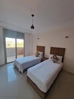 a bedroom with two beds and a large window at appartement de luxe face la marllette in Marrakech