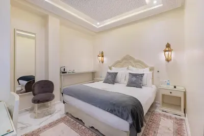 a white bedroom with a large bed and a chair at HOTEL RIAD CHAMI in Marrakech