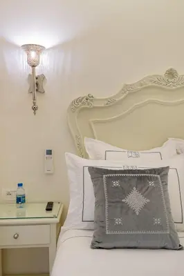 a white bedroom with a bed with a white headboard at HOTEL RIAD CHAMI in Marrakech